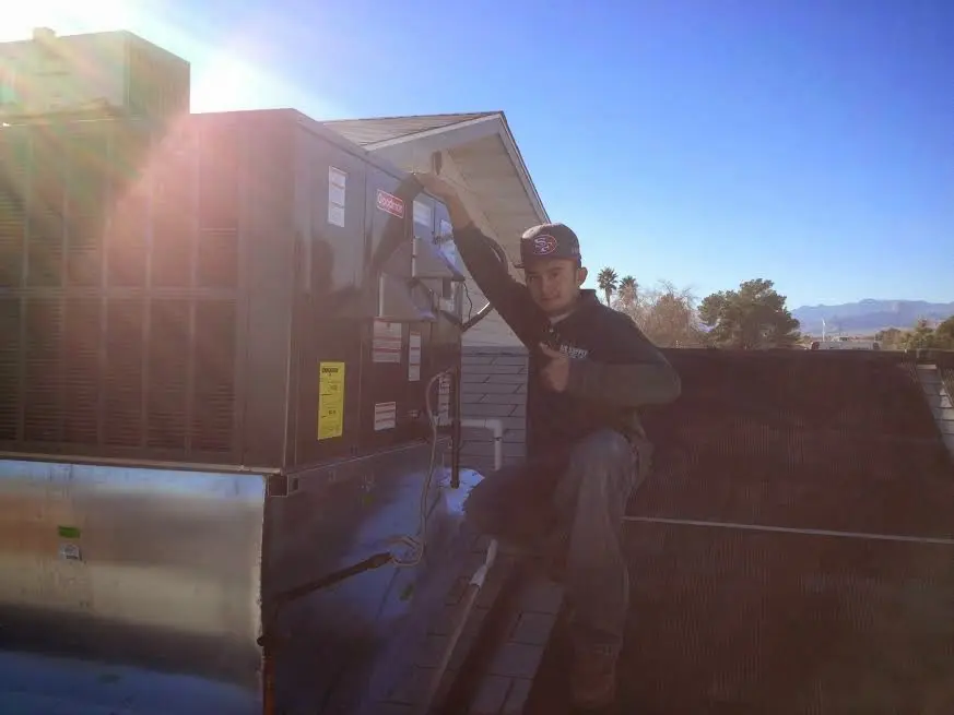 HVAC technician performing Heat Pump Repair on a rooftop unit in Essex