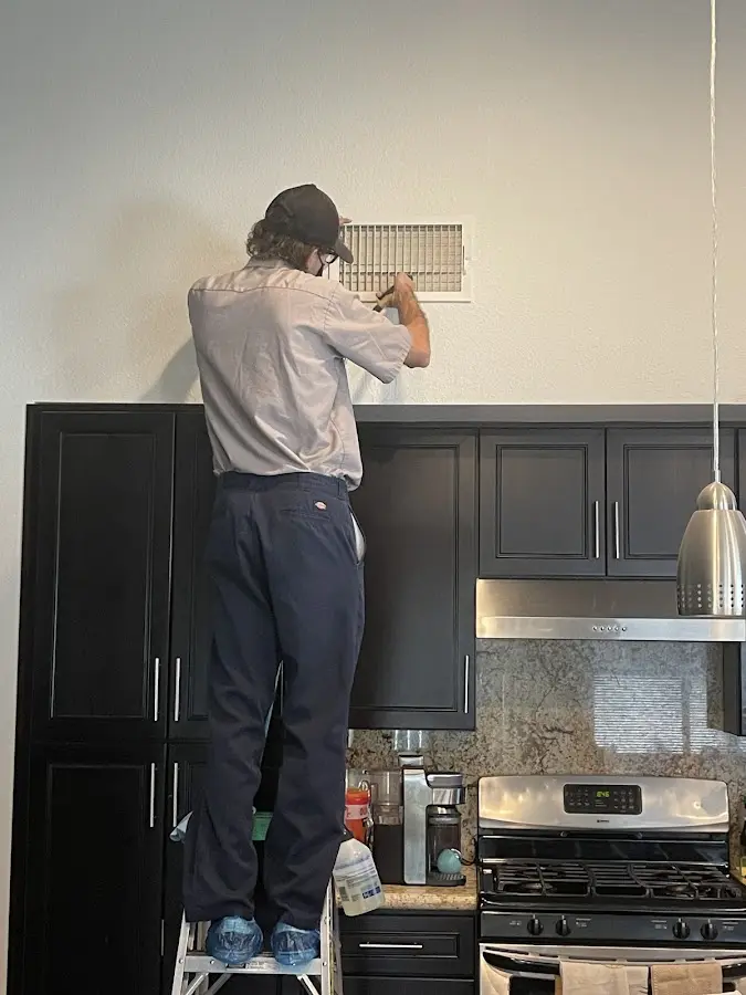 Technician inspecting an air vent during HVAC service in Essex